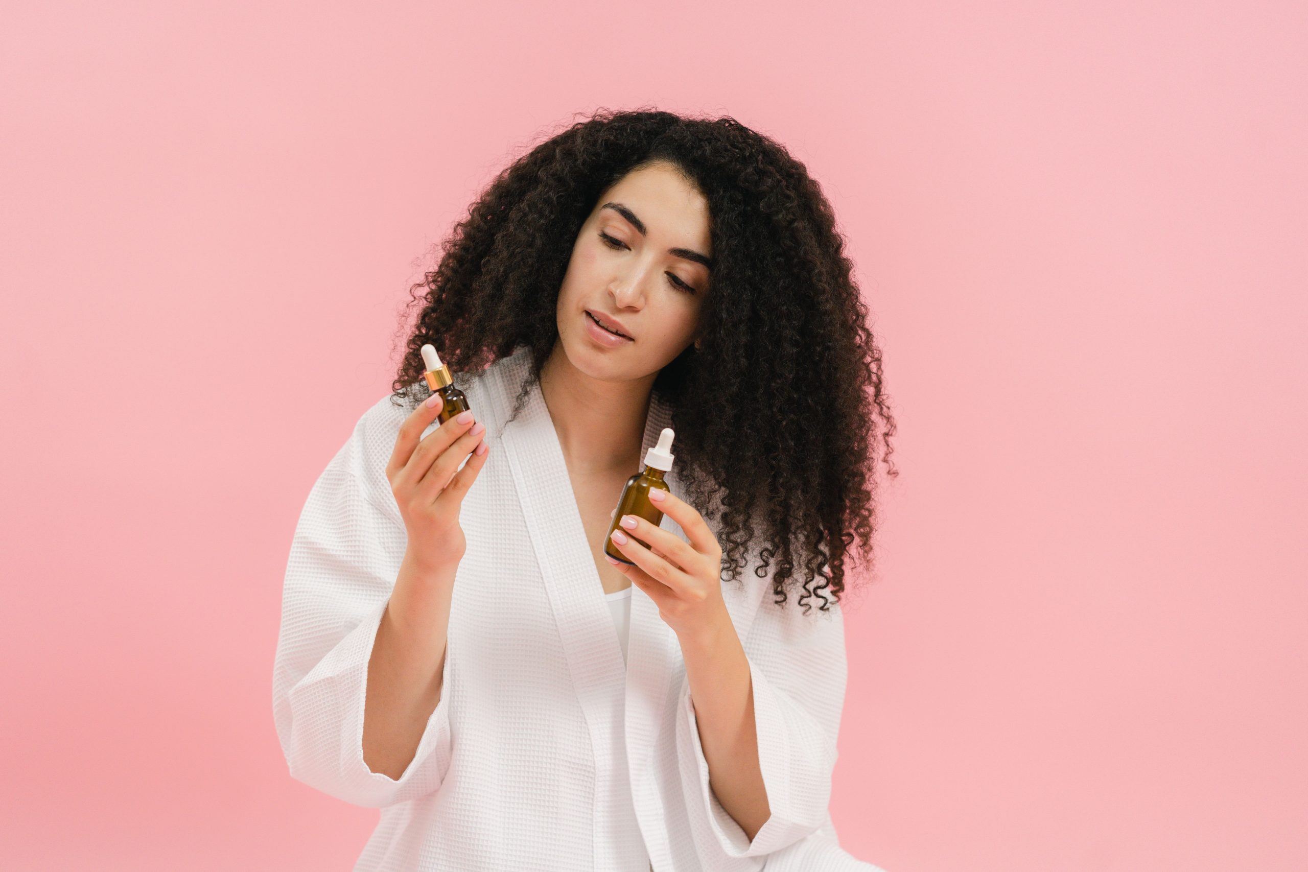 Femme cheveux boucles compare deux bouteilles huile