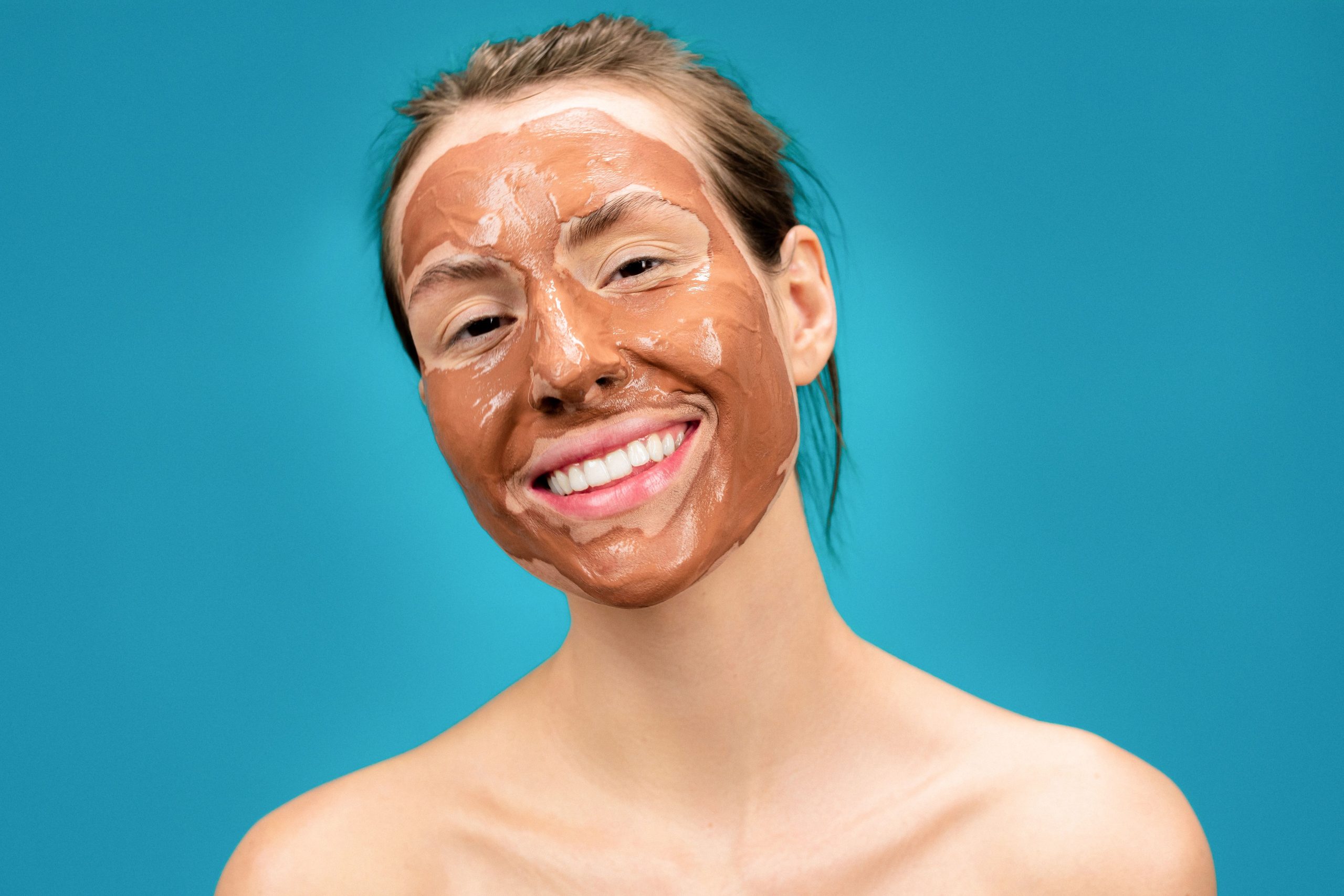 Portrait femme souriante avec masque facial argileux