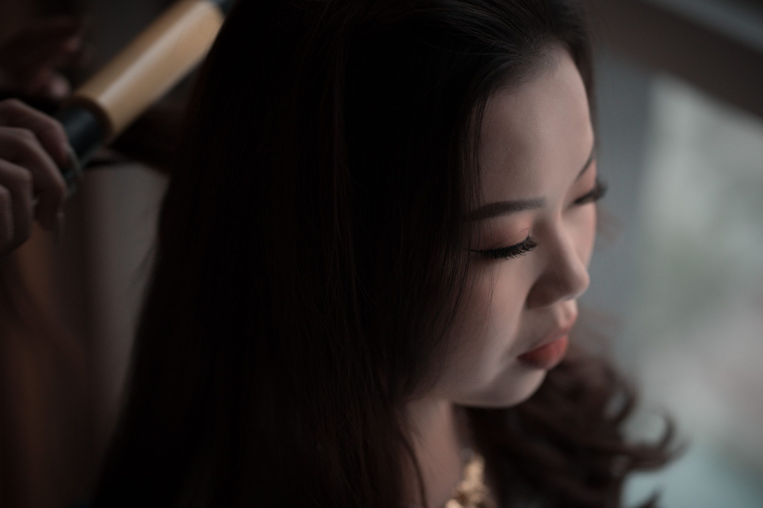 Femme asiatique se coiffant avec un fer à boucler
