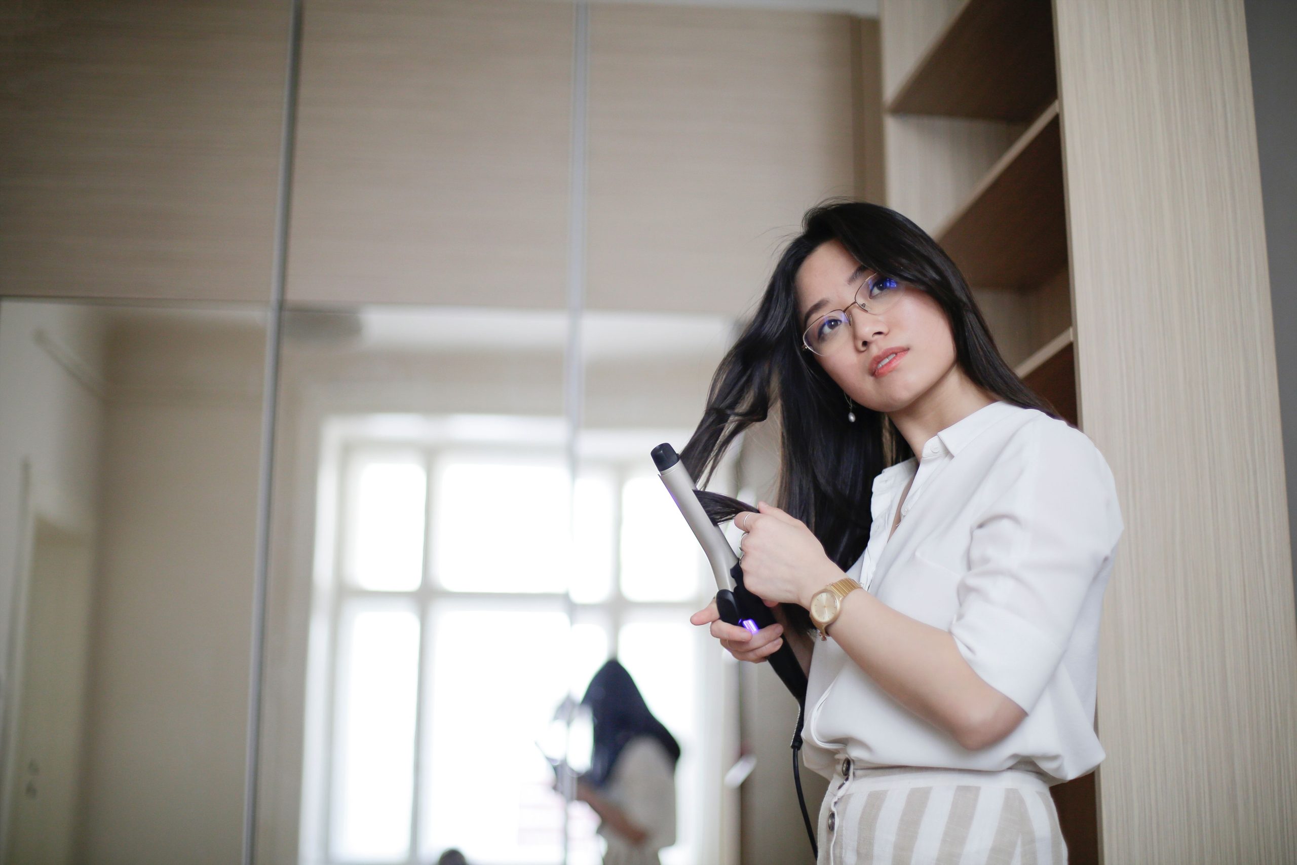 Femme asiatique se boulant les cheveux au fer le matin