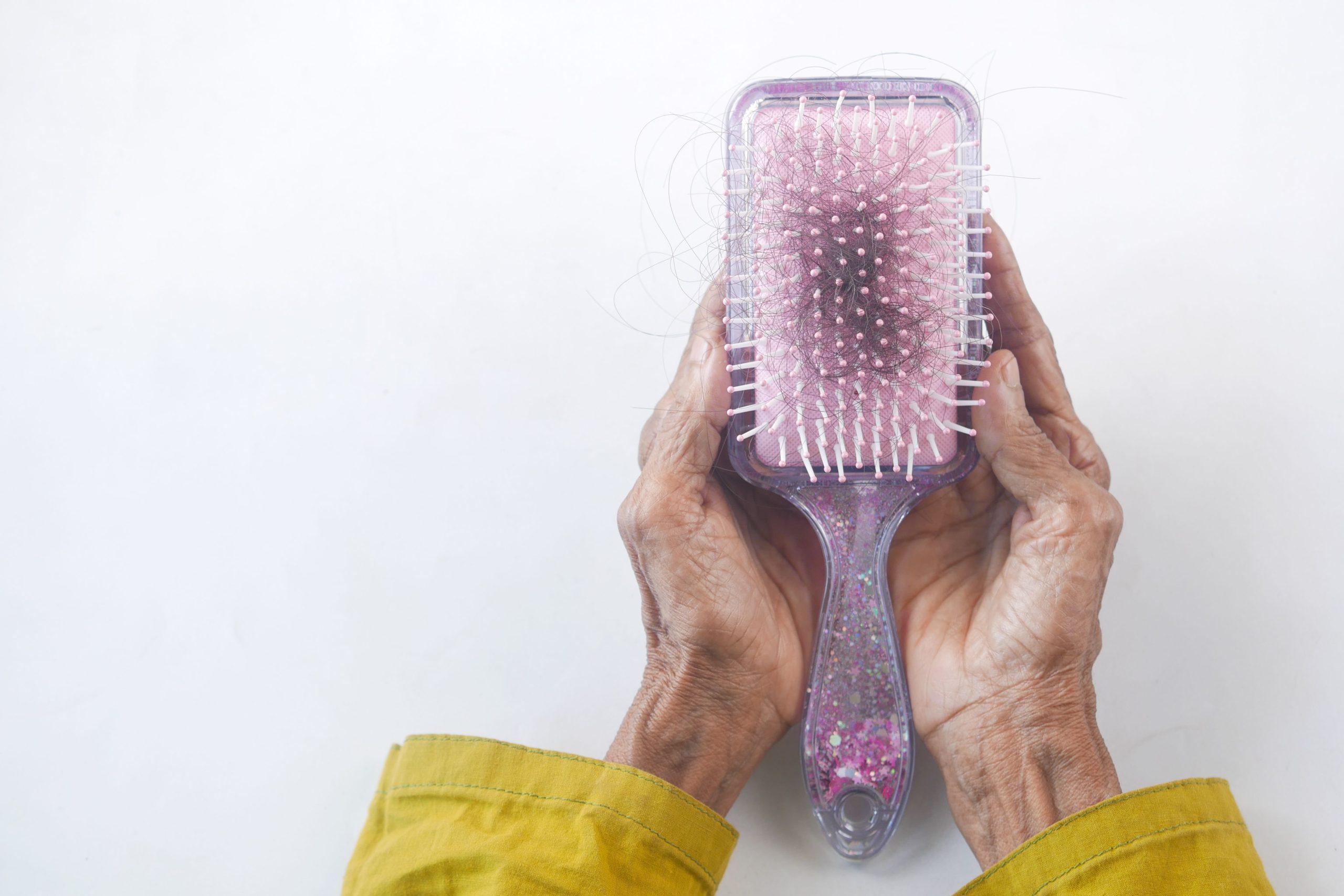Mains seniors avec brosse à cheveux et mèches