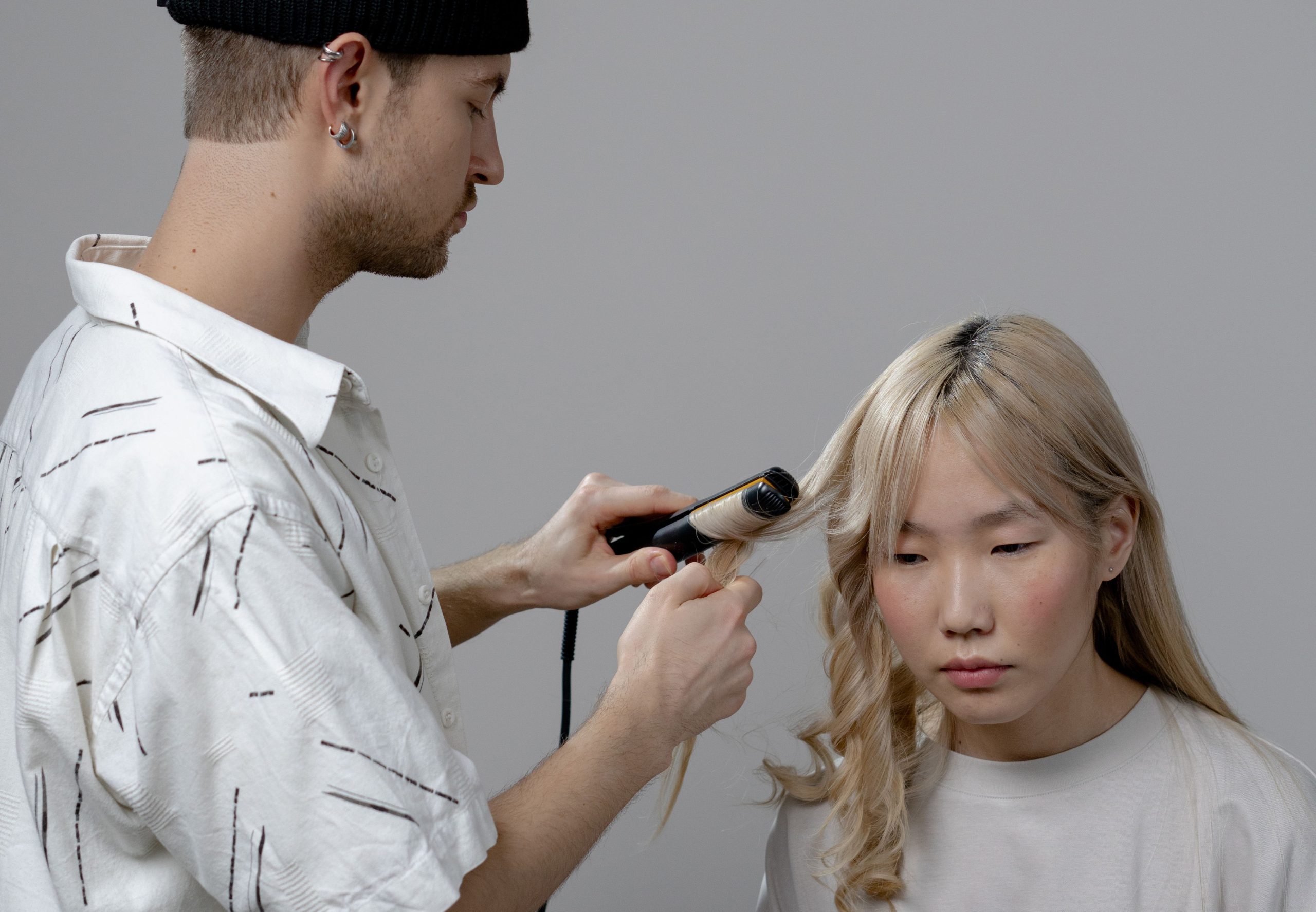 Coiffeur utilisant un fer à boucler en salon professionnel