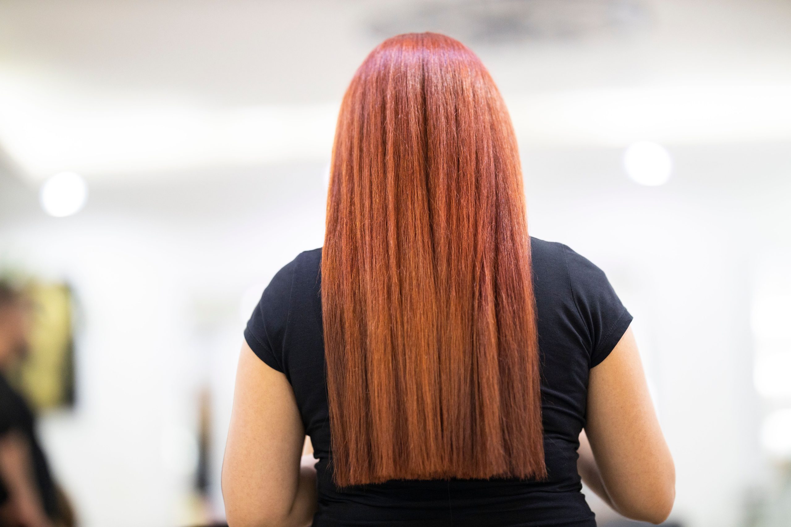 Femme cheveux rouges lisses coupe fraîche salon.