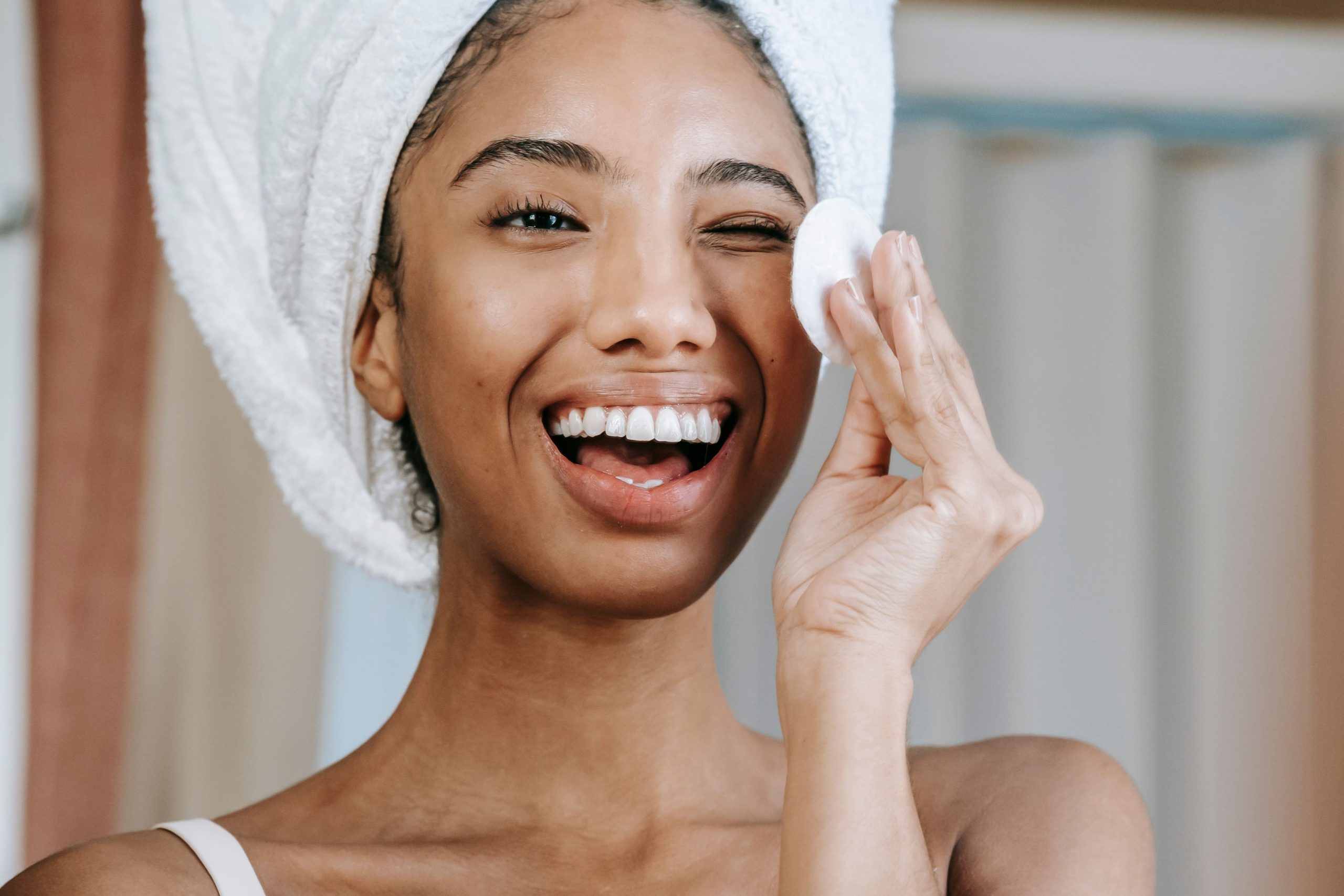 Femme souriante nettoyant visage au coton matin