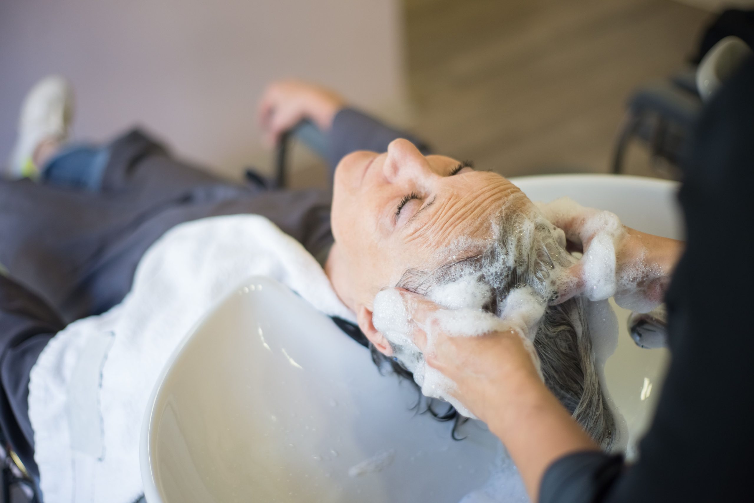 Femme recevant un massage capillaire professionnel au salon.
