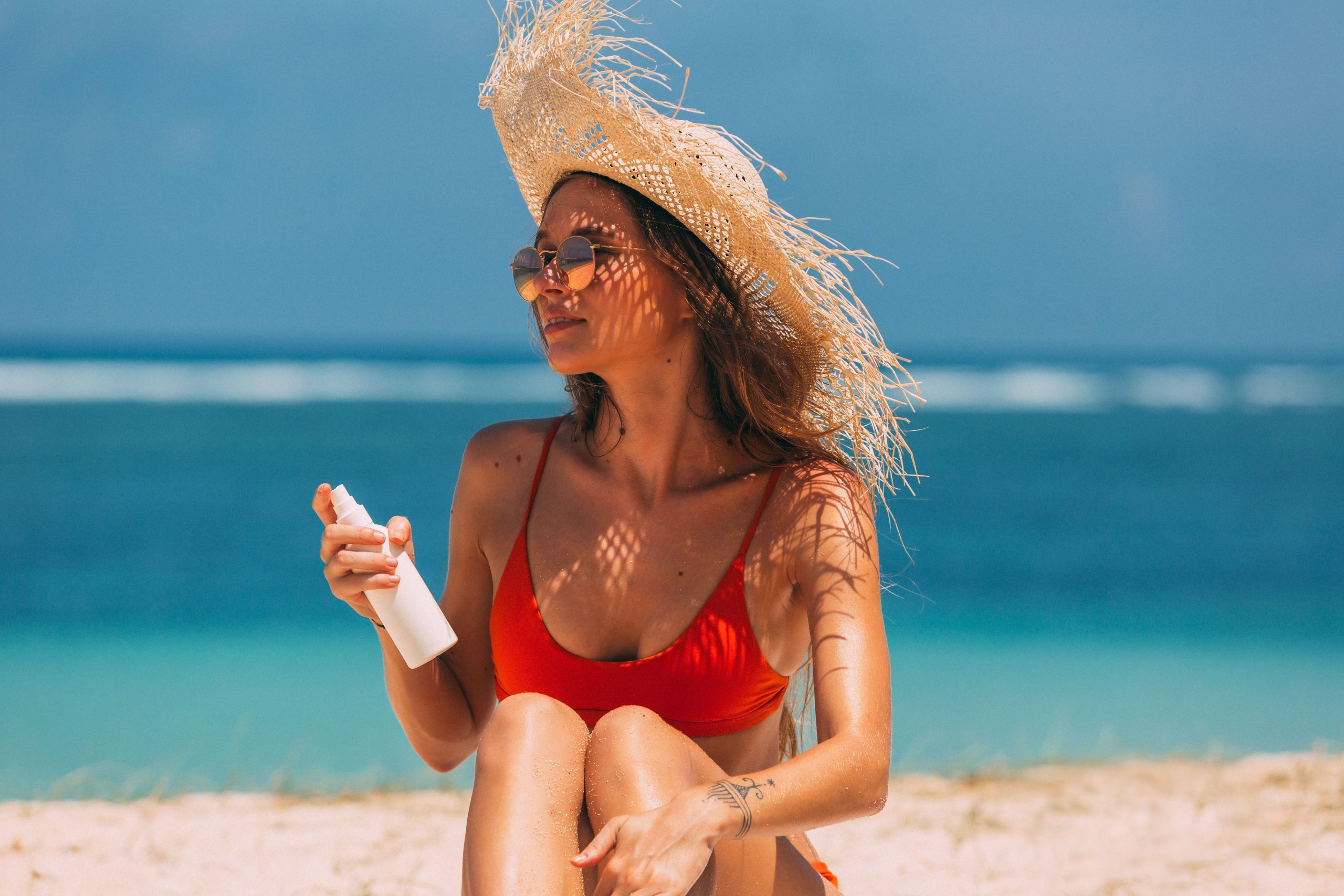 Femme élégante avec chapeau de paille à la plage