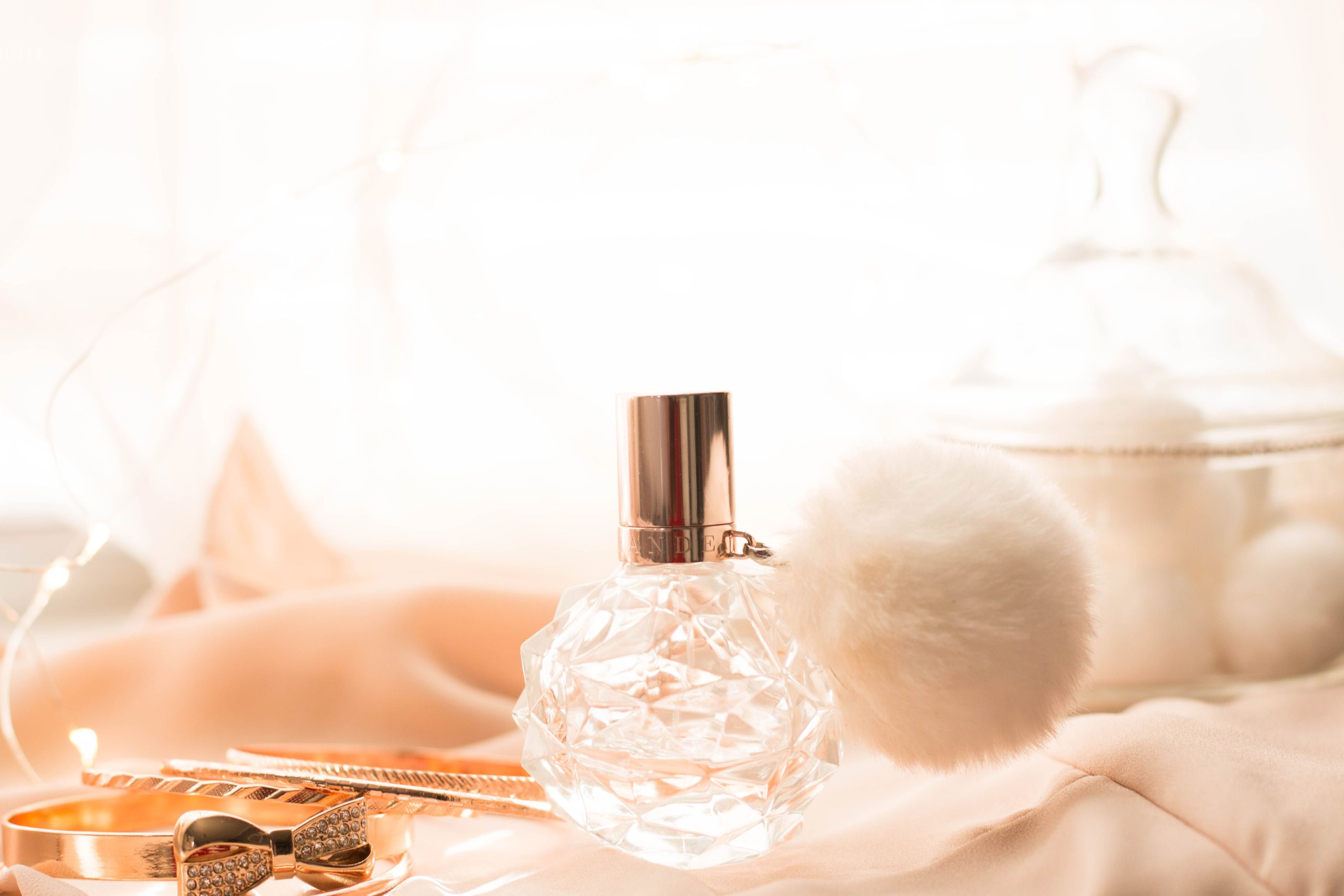 Flacon de parfum luxueux avec accessoires dorés sur tissu rose
