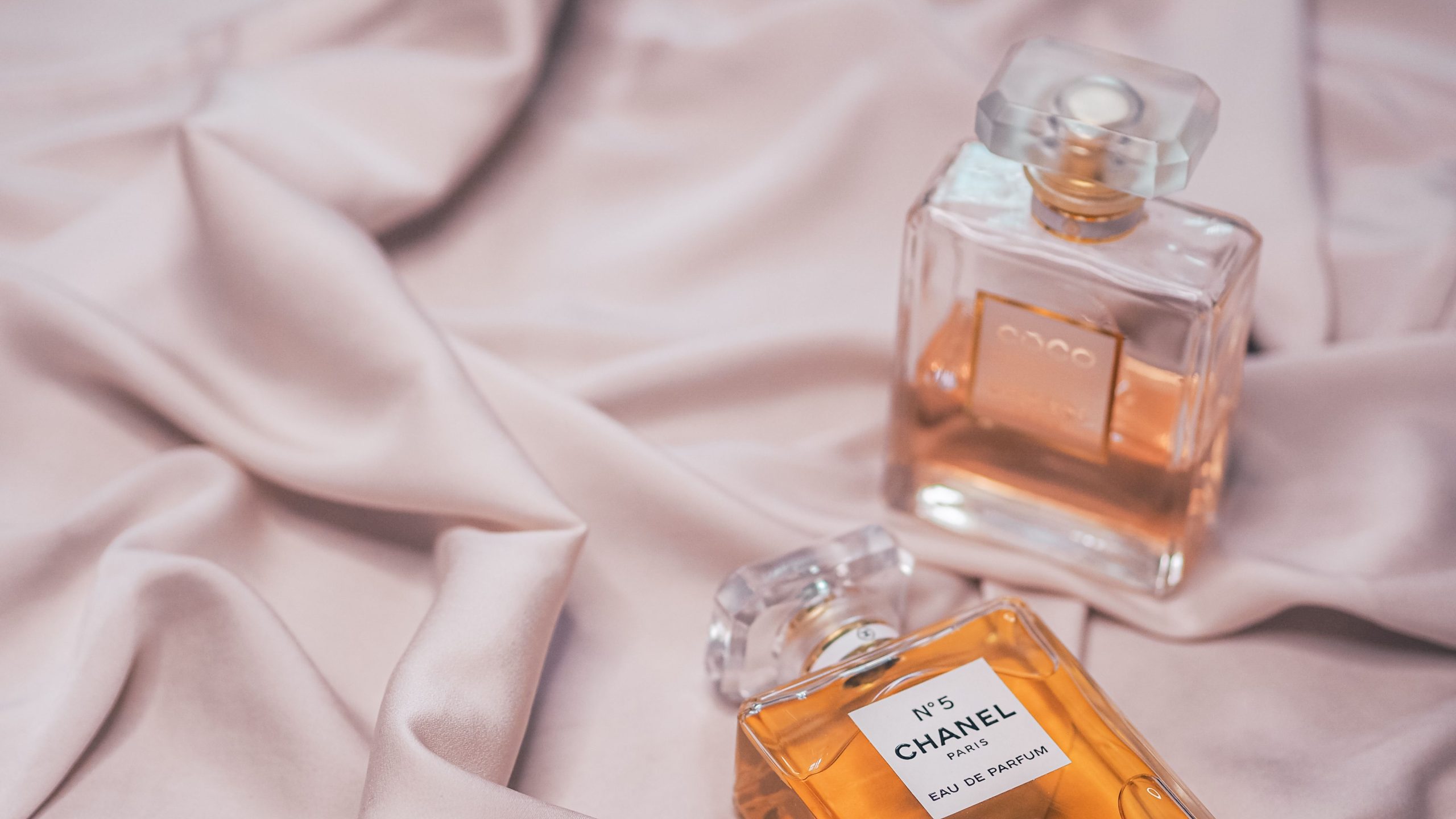 Flacons de parfum luxueux sur soie rose douce et élégante