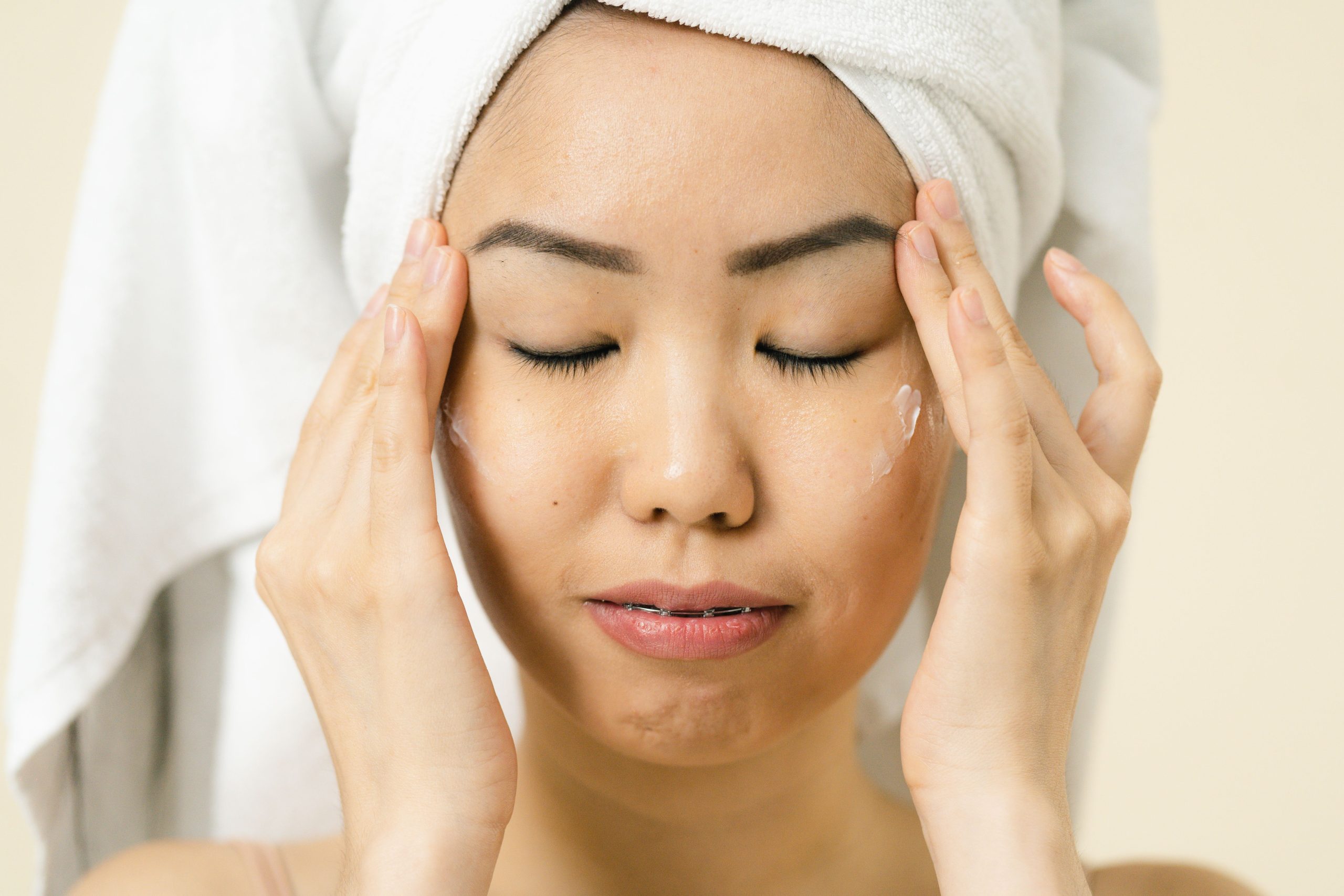 Femme asiatique appliquant moisturizer après douche