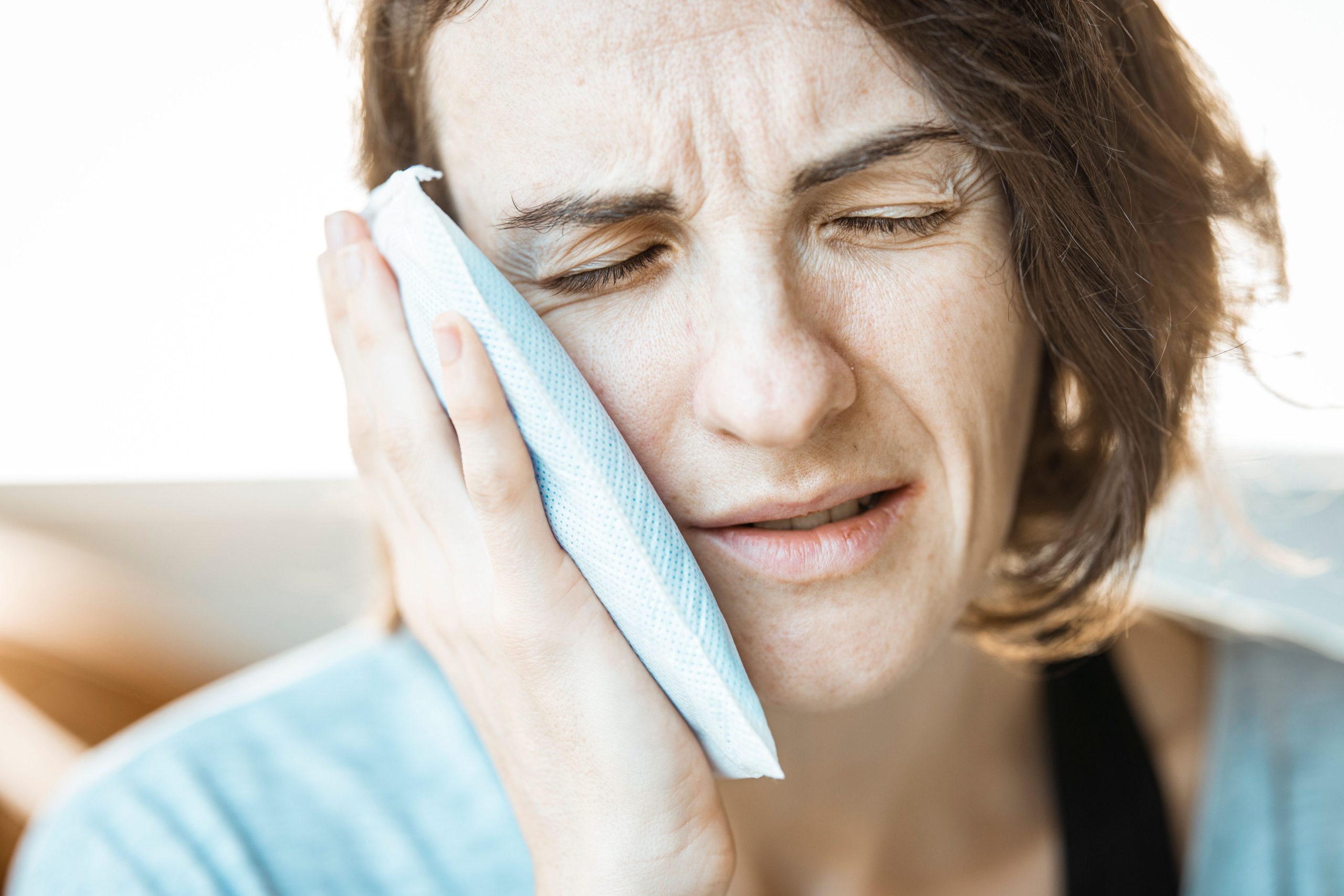Femme appliquant une compresse froide sur sa joue