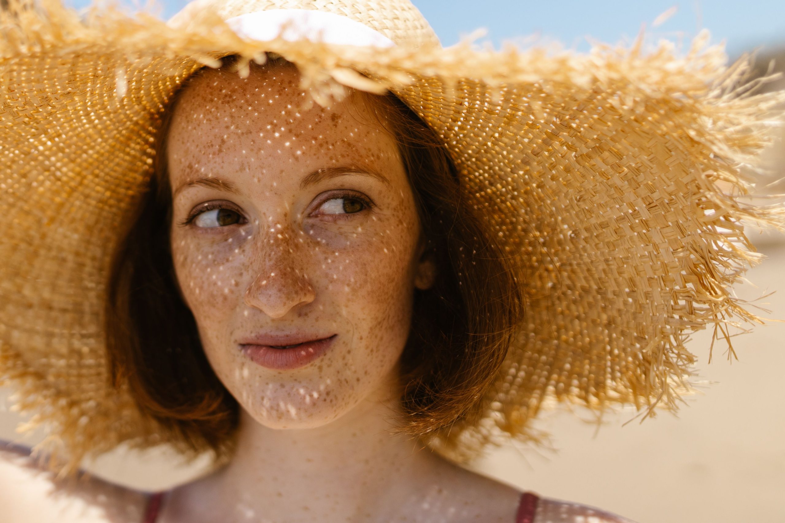 Femme souriante avec chapeau de paille à la plage